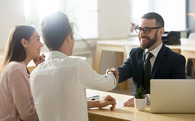 smiling lawyer, realtor or financial adviser handshaking young couple thanking for advice